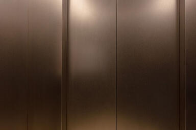 Elevator return wall and door in Stainless Steel with Sandstone at Baashyaam