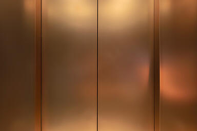 Elevator doors in Fused Bronze with Seastone finish at Castel Royale, Pune, Indi