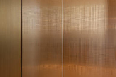 Detail of elevator door in Fused Bronze with Satin finish and custom Thatch