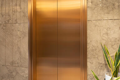 Elevator doors in Fused Bronze with Satin finish; elevator transom