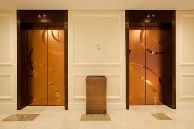 Elevator doors shown in Fused Bronze with Mirror finish and ECO205H Eco-Etch 