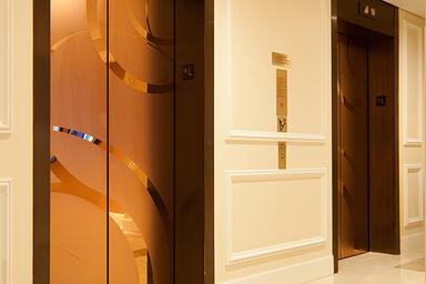 Elevator doors shown in Fused Bronze with Mirror finish and ECO205H Eco-Etch 
