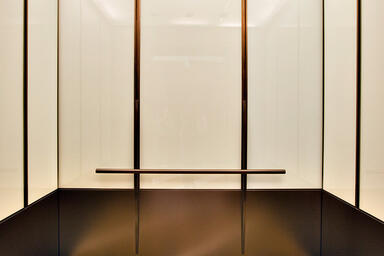 Elevator interior with lower panels in Fused Nickel Silver with Sandstone finish